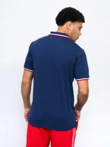 Remera polo azul con cierre, puños y cuello con detalle tricolor. Incluye logo de Umbro y escudo del Club Nacional de Football.