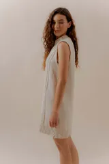 Vestido corto tejido color beige, sin mangas y con cuello redondo.