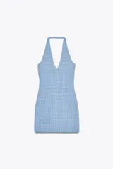 Minivestido celeste de tejido elástico con textura, cuello halter, escote en V, bolsillos simulados y cierre frontal con botones metálicos.
