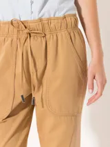 Pantalón babucha color verde militar, confeccionado en tejido de punto y plano. Tiene cintura elastizada con cordón ajustable y largo al tobillo.