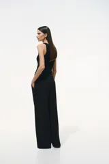Pantalón sastrero negro de corte holgado con tiro alto y cierre con corchete y botón ocultos. Piernas amplias con pinzas, pliegues adelante y atrás, bolsillos al bies y bolsillos decorativos atrás.