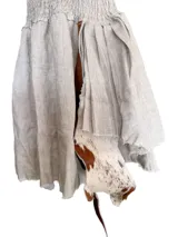 Vestido corto color beige, confeccionado en lino con tiras de cuero vacuno. Presenta elástico en la parte superior y falda irregular en lino y cuero.