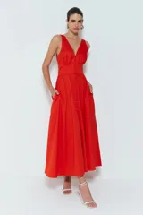 Vestido midi rojo de satén de algodón con escote en V, cintura ajustada, falda acampanada con bolsillos a la cadera y botones del mismo color que la tela. Presenta cierre frontal con botones y espalda con abertura.