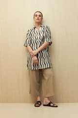 Vestido corto con estampado de líneas onduladas en blanco, negro y beige. Tiene cuello tipo solapa, escote en V y mangas 3/4.