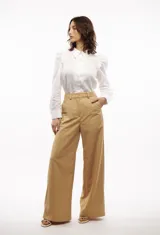Camisa blanca de lino con corte clásico, cuello camisero, mangas largas con puños abotonados y volados en los hombros.
