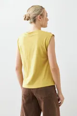 Remera verde pistacho de corte recto, con cuello en V y botones decorativos en los hombros.