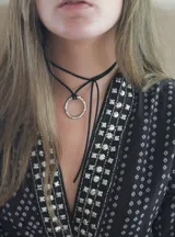 Gargantilla de cuero sintético negro con dije circular de alpaca.