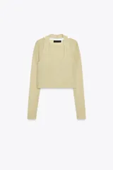 Top color crema de punto, con cuello redondo, manga larga y detalle de bajo superpuesto.