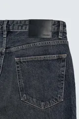 Pantalón de jean de tiro medio, color gris oscuro con efecto lavado, corte ajustado en la parte superior y acampanado desde la rodilla, con cinco bolsillos y cierre frontal con cremallera y botón.
