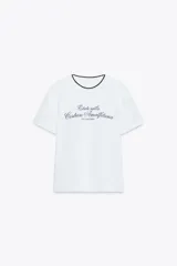 Camiseta blanca de algodón con cuello redondo y detalle de tricot a contraste en azul marino. Estampado frontal con texto "Estate sulla Costiera Amalfitana" en azul marino.