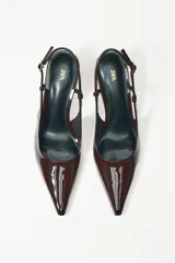 Zapato de tacón destalonado color marrón charol, con punta fina y tira trasera con hebilla.