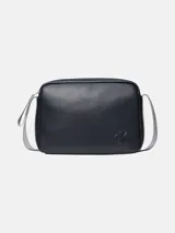 Cartera tipo camera bag de Calvin Klein, color azul marino oscuro, con textura de cuero granulado. Presenta un logo CK grabado en bajo relieve en el frente y una correa ajustable de tela gris claro.