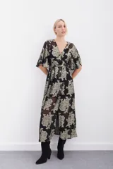 Vestido largo negro con estampado floral dorado en lurex, escote en V cruzado, mangas al codo, cintura elastizada con lazo y viso al tono con breteles regulables y puntilla en el escote.