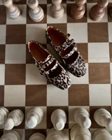 Ballerinas con estampado animal print de leopardo, con dos tiras sobre el empeine y hebillas doradas. Interior color naranja.