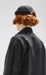 Camisa negra de manga corta, corte oversize, confeccionada en poplin 100% algodón. Presenta dos bolsillos delanteros, uno con solapa y otro con ojal y botón.