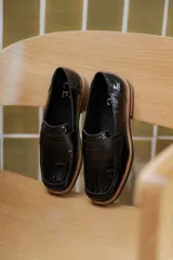 Mocasines de cuero marrón con diseño de cocodrilo, suela plana y detalle de antifaz en el empeine.