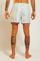 Short de baño blanco con estampado de hojas en tonos celeste y naranja, con cordón ajustable en la cintura.