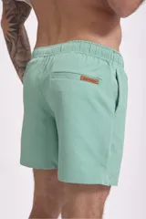 Short de baño color verde oliva con textura de rayas finas en relieve y cordón de ajuste blanco en la cintura.