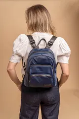 Mochila funcional color beige con detalles en negro, que incluye dos compartimentos con cierre y un bolsillo frontal para fácil acceso.