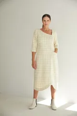 Vestido midi color crudo con estampado a cuadros, escote asimétrico, manga 3/4 con detalle de tajo y bolsillo lateral.