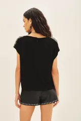 Remera negra de viscosa con escote en V, manga corta y bordado de canutillos y mostacillas color peltre en los hombros.