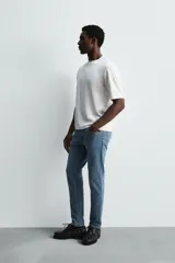 Pantalón de jean negro, corte slim fit, con tiro medio, cinco bolsillos, efecto lavado y cierre frontal con cremallera y botón.