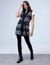 Chaleco largo tejido con cuello solapa, bolsillos delanteros, pasadores en la cintura y lazo para ajustar. Diseño con patrón de zigzag en blanco y negro.