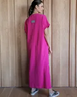 Vestido largo color crudo con cuello redondo y mangas cortas con ribete negro. Tiene corte recto y aberturas laterales en el ruedo.