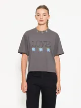 Remera gris con estampado frontal de la palabra 'Love' y tres flores azules.
