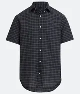 Camisa de hombre de corte clásico, color gris oscuro con estampado de cuadros blancos, cuello abotonado, manga corta y cierre frontal con botones blancos.