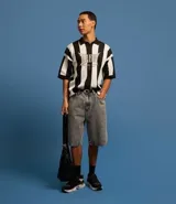 Bermuda de jean gris con corte amplio, cierre con botón y cremallera, bolsillos y pespuntes en contraste.