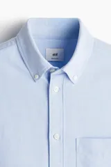 Camisa celeste de algodón Oxford con cuello abotonado, manga corta, bolsillo de parche en el pecho y corte regular.