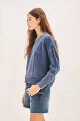 Sweater celeste de punto con diseño de trenzas, cuello redondo y corte holgado.