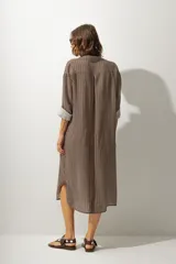 Vestido camisero midi de cuero color marrón, con cuello solapa, manga larga remangada y botones frontales.