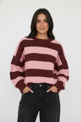 Sweater de tejido grueso, holgado, con cuello redondo y mangas largas. Presenta un diseño de rayas horizontales anchas en color rosa claro y marrón oscuro.