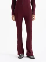 Pantalón de pierna recta color bordó, confeccionado en viscosa con elastano. Presenta cintura elastizada, costuras decorativas en el frente y broches metálicos con logo grabado en las botamangas.