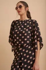 Blusa negra con estampado de estrellas color crema con borde rosa, de corte holgado y mangas cortas amplias.
