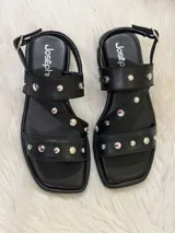 Sandalias negras de cuero sintético con tiras cruzadas y apliques de tachas plateadas.