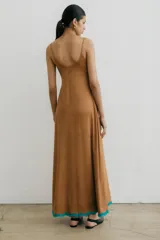 Vestido largo color marrón de gamuza con breteles finos, escote redondo, bordado floral turquesa en el escote y galón turquesa en el ruedo.