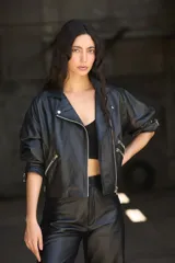 Chaqueta de cuero ovino negra, estilo biker, con cuello con solapa, cierre frontal asimétrico con cremallera, mangas globo con puños ajustables con cremallera y cinturón con hebilla en la cintura.