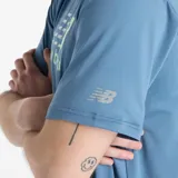 Remera celeste de hombre, marca New Balance, modelo Performance. Tiene mangas cortas y logo estampado en el pecho con diseño multicolor.