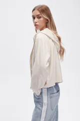 Campera color crudo de lino con capucha, cierre frontal y bolsillos plaqué.