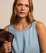 Musculosa de jeans celeste con recortes y cierre por botón.