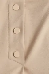 Short pollera color beige de tiro alto con elástico en la cintura, pliegues y botones decorativos en el frente.