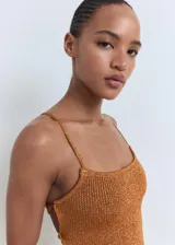 Vestido corto de punto acanalado color ocre, con escote cuadrado y tirantes finos. Presenta espalda descubierta con tirantes cruzados y cierre de lazo.