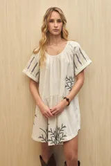 Vestido corto color crudo con bordado de hojas en el ruedo y en las mangas.