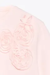 Camiseta blanca de algodón de manga corta y cuello redondo con detalle de flores en relieve en el frente.