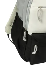 Mochila de diseño color block con tres secciones principales: superior gris claro, media blanca y inferior negra. Cuenta con múltiples compartimentos con cierres de cremallera y tiradores de cordón anudado.