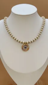 Collar de cuentas grises y blancas con dijes dorados con incrustaciones de circonitas.