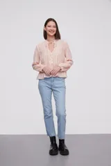 Blusa blanca con rayas verticales, cuello con lazo, mangas largas y corte holgado.